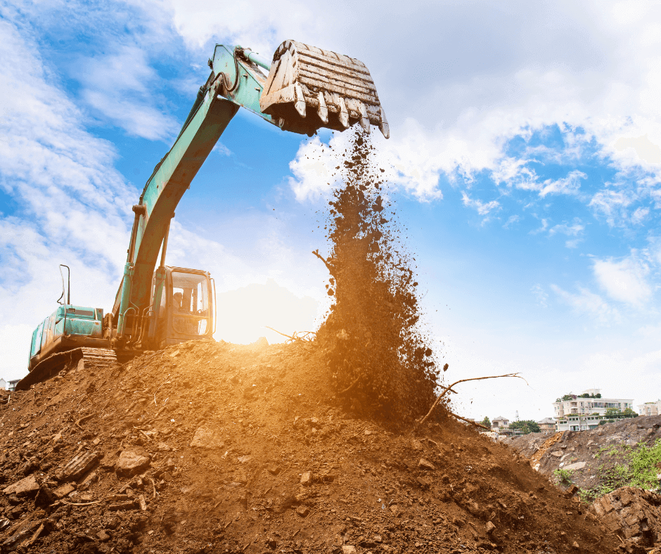 Excavator dumping dirt on the ground during the day.