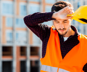 Man on a construction site wiping sweat off his forehead. 