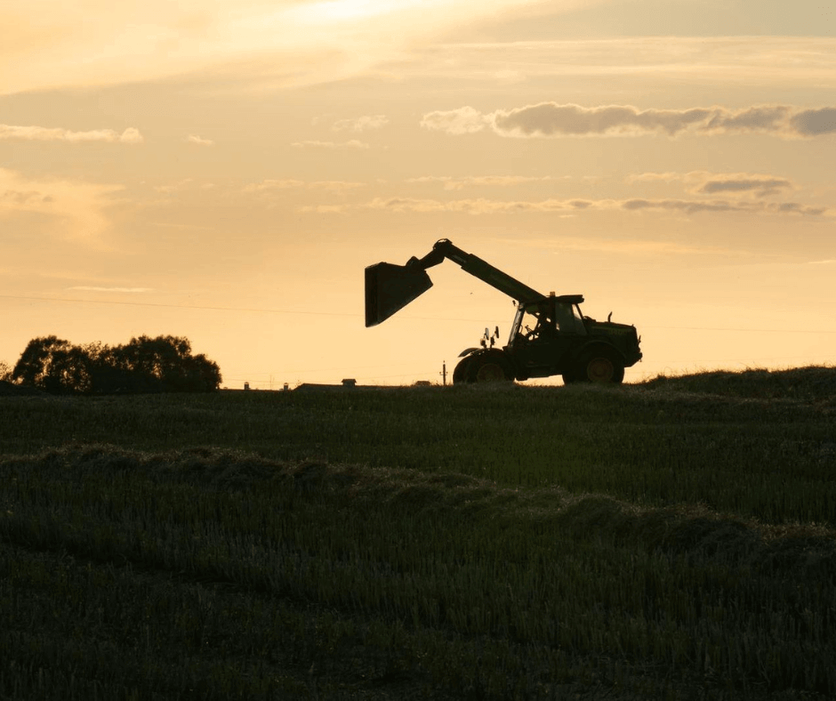 Rentable tractor sitting in a field during sunset.